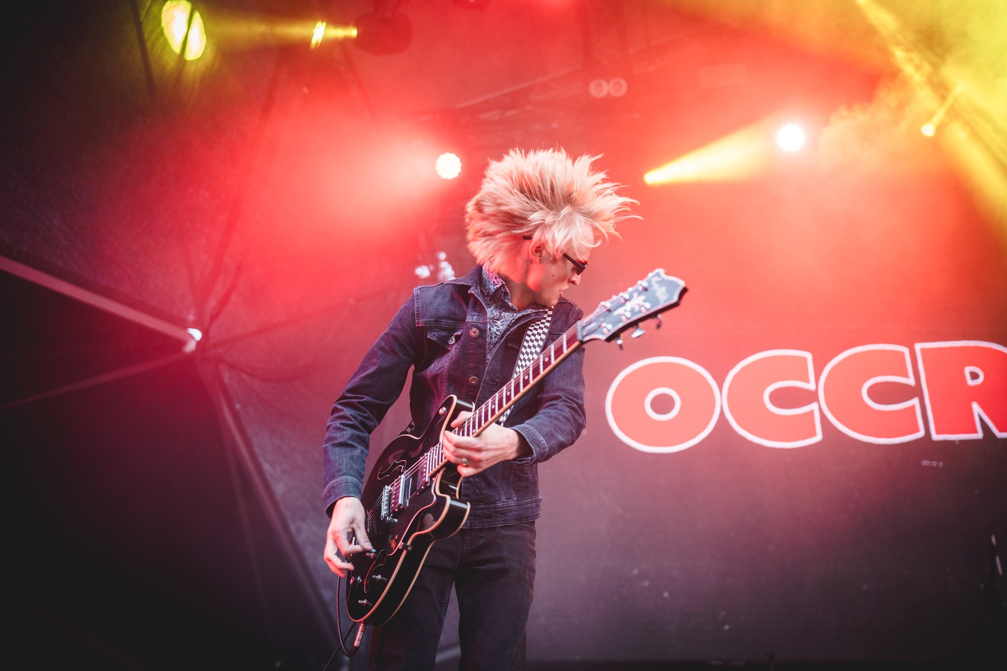 Occrasy guitarist performing under red and yellow lights at Alive Festival Saturday