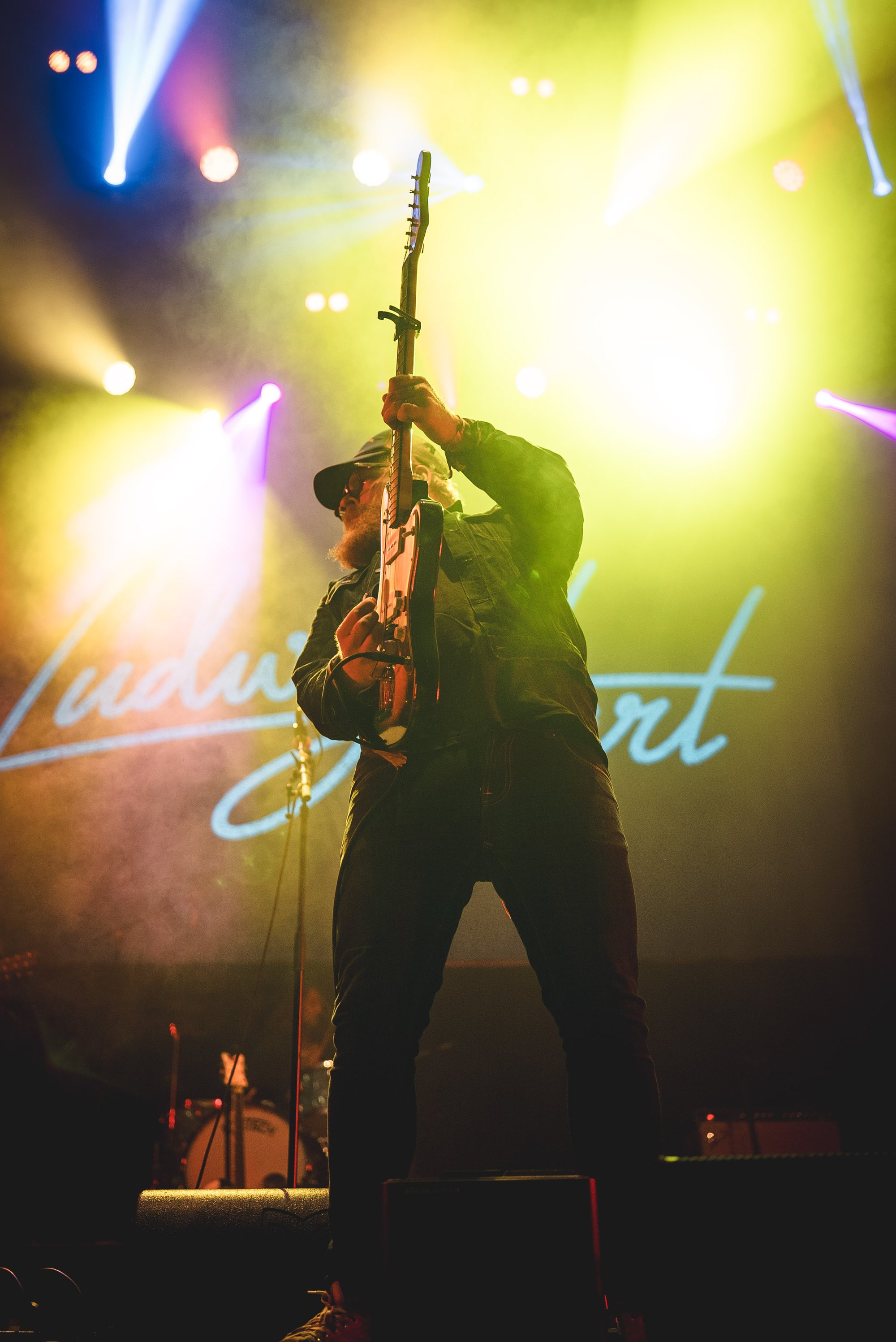 Ludwig Hart performing with his guitar under yellow lights