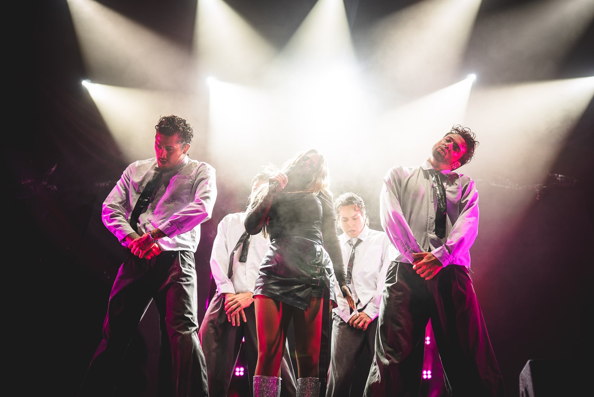 Felicia performing with dancers beneath white stage lights